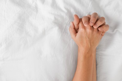 Photo of Lovely couple holding hands in bed, top view. Space for text