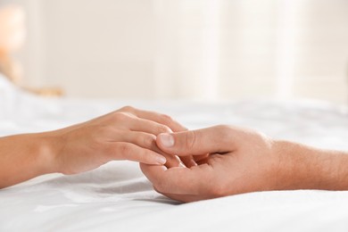 Photo of Lovely couple holding hands in bed, closeup