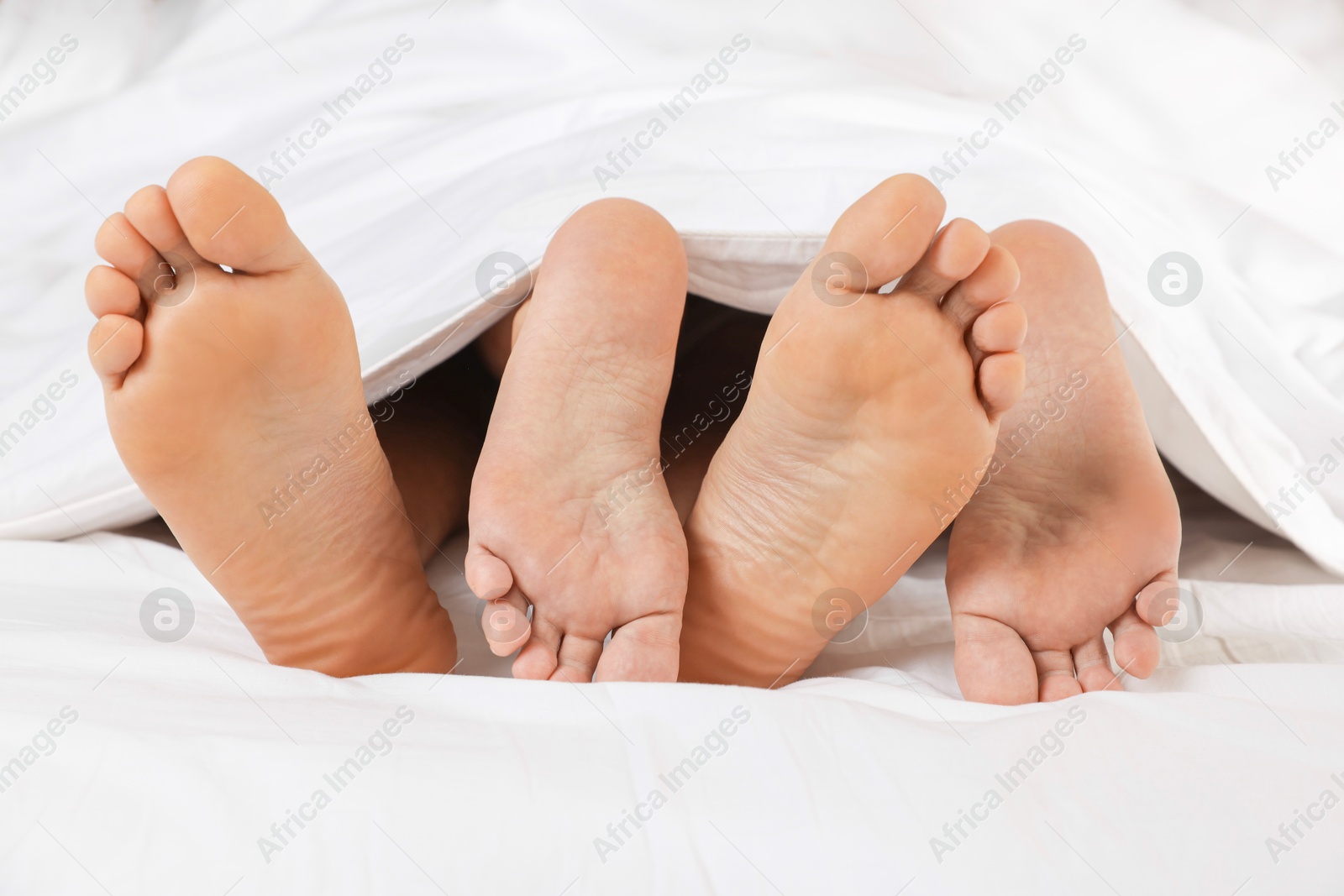 Photo of Couple lying in bed with white sheets, closeup