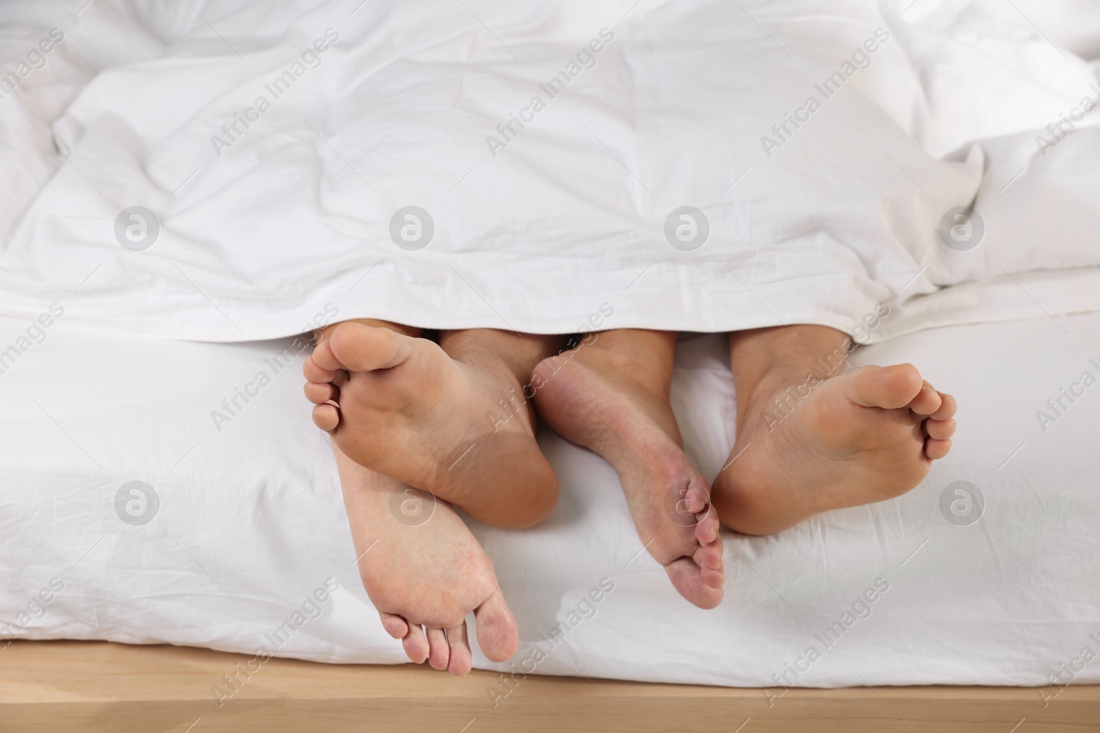 Photo of Couple lying in bed with white sheets, closeup