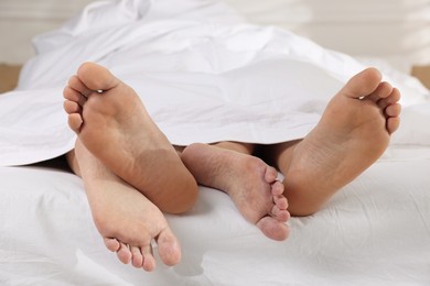 Photo of Couple lying in bed with white sheets, closeup