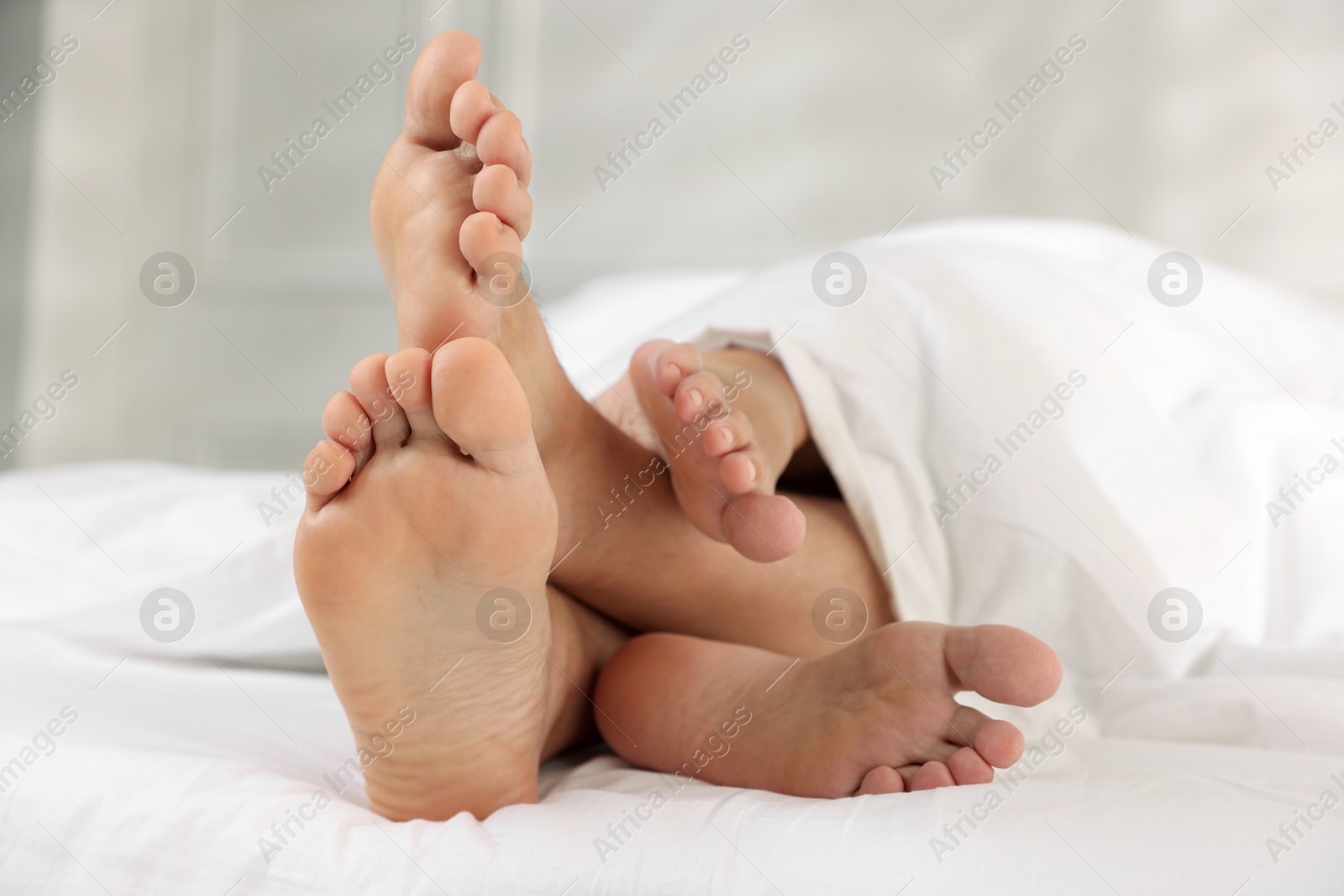 Photo of Couple lying in bed with white sheets, closeup