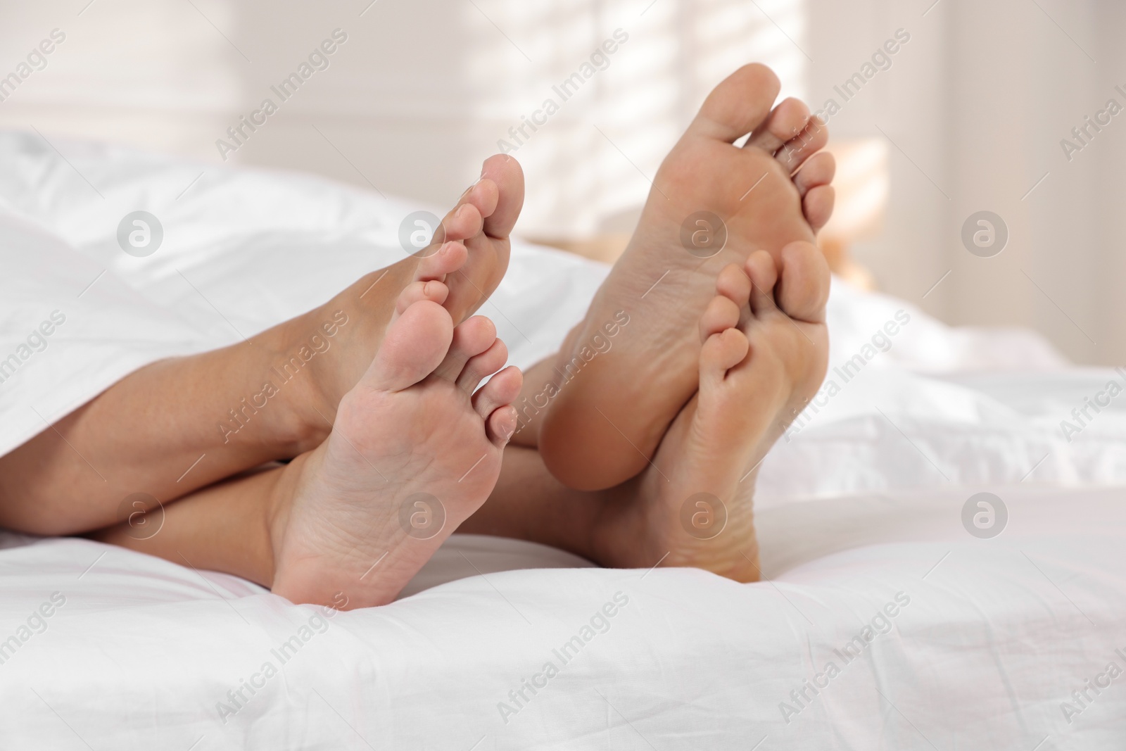 Photo of Couple lying in bed with white sheets, closeup