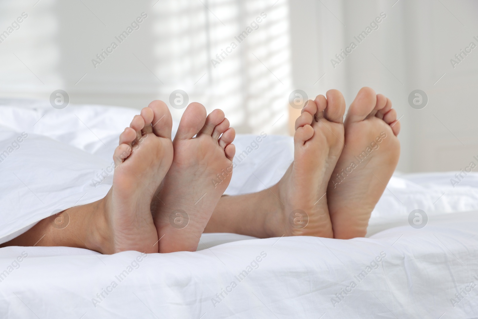 Photo of Couple lying in bed with white sheets, closeup