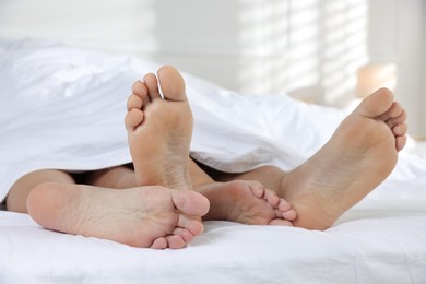 Photo of Couple lying in bed with white sheets, closeup