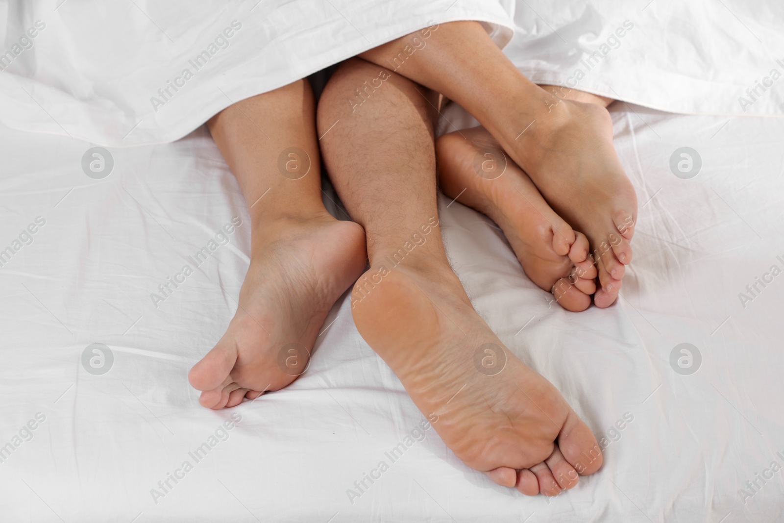 Photo of Couple lying in bed with white sheets, closeup