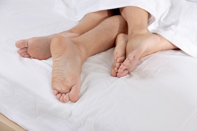 Photo of Couple lying in bed with white sheets, closeup