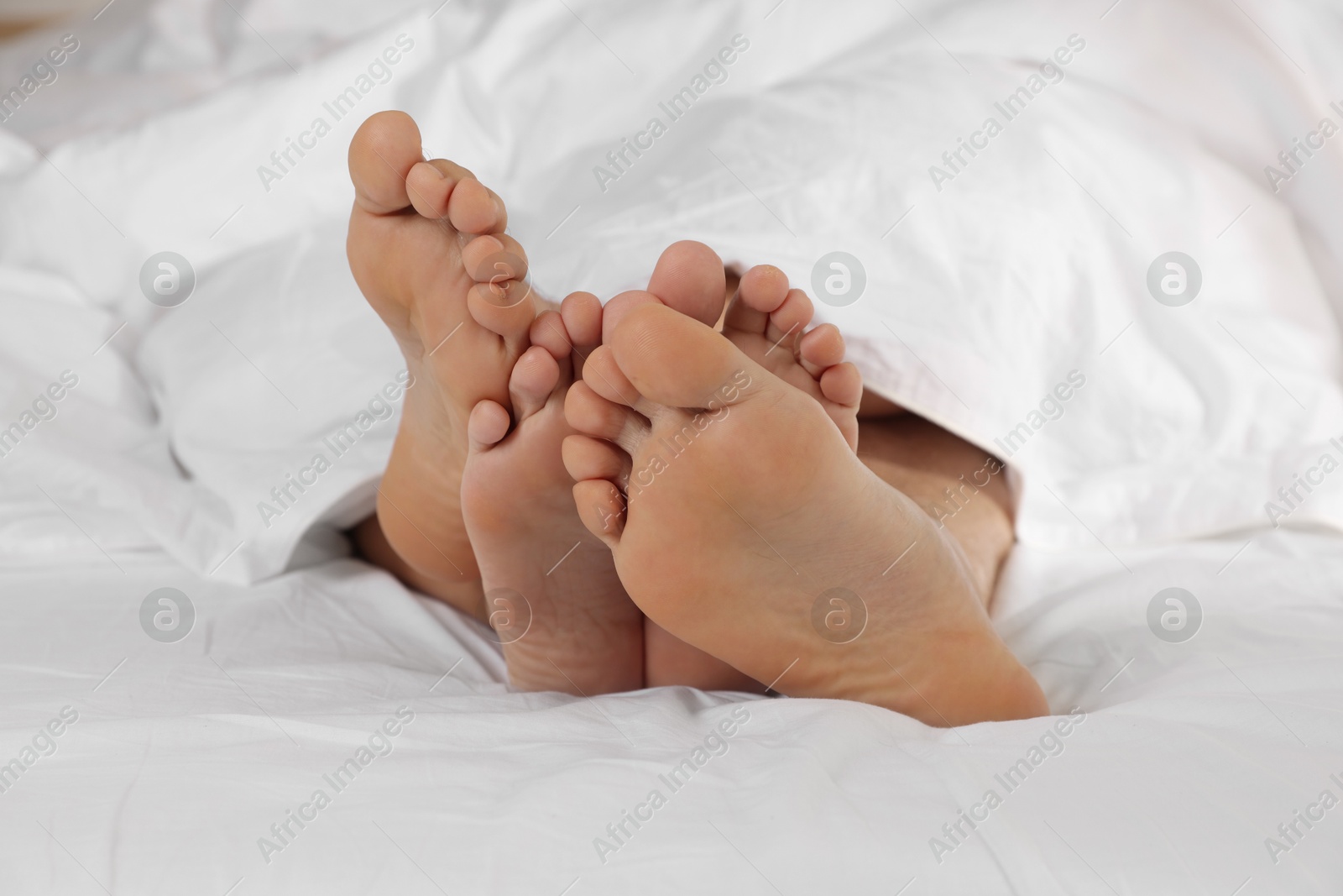 Photo of Couple lying in bed with white sheets, closeup