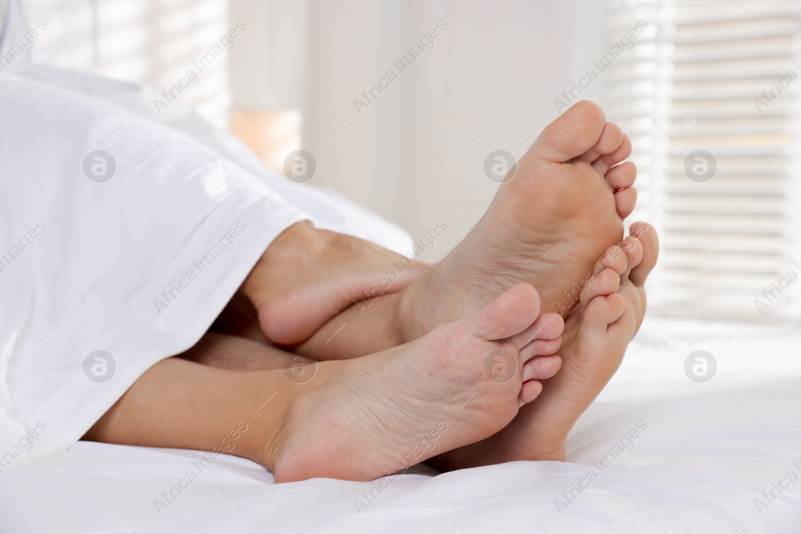 Photo of Couple lying in bed with white sheets, closeup