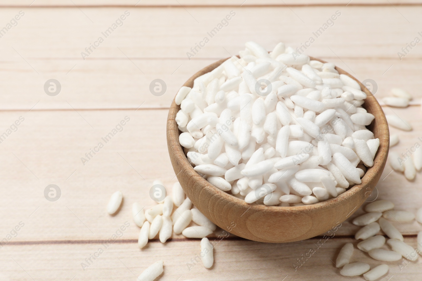 Photo of Puffed rice in bowl on wooden table, closeup. Space for text