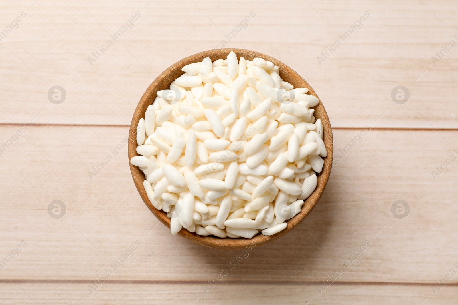 Photo of Puffed rice in bowl on wooden table, top view