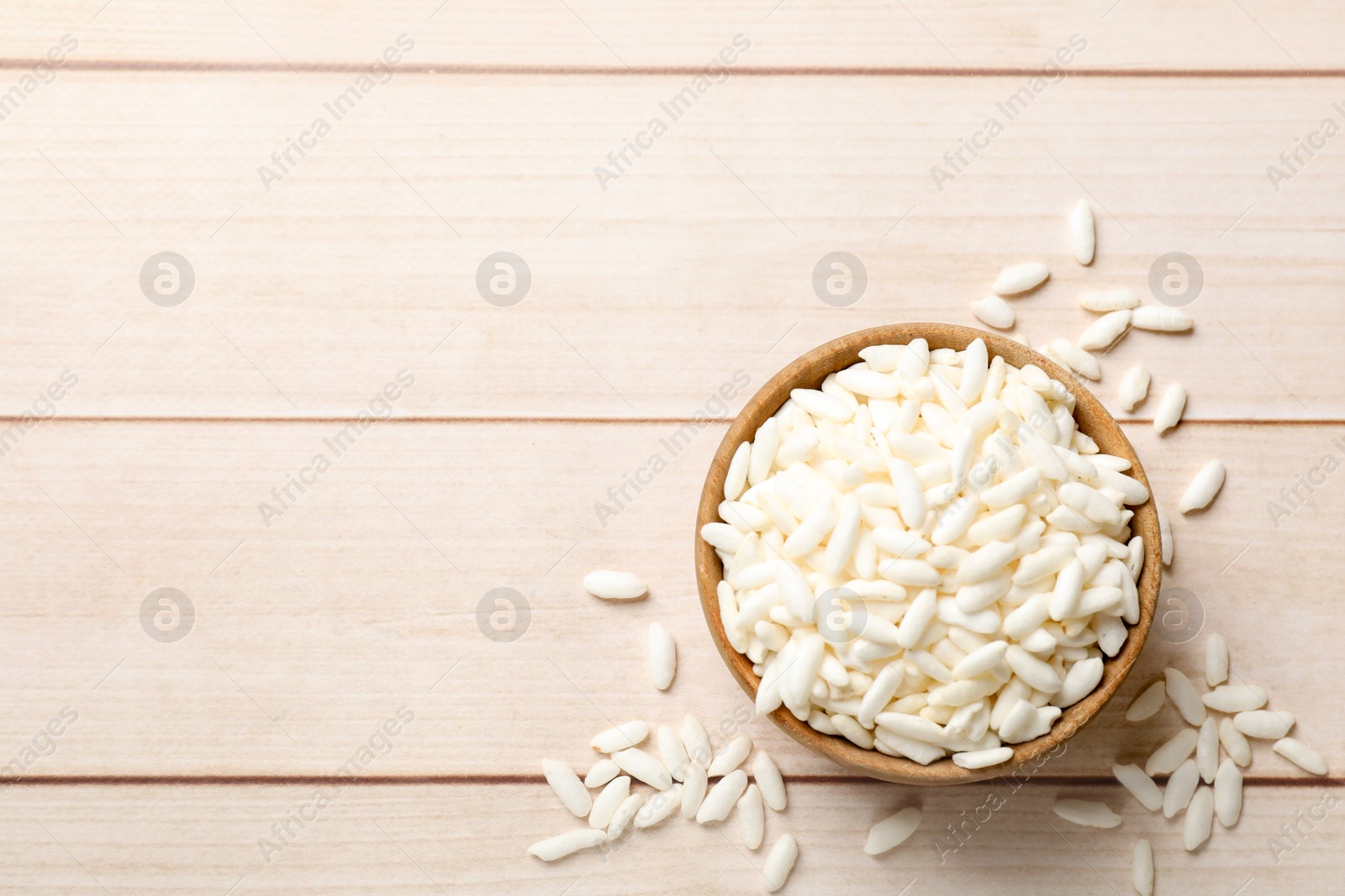 Photo of Puffed rice in bowl on wooden table, top view. Space for text