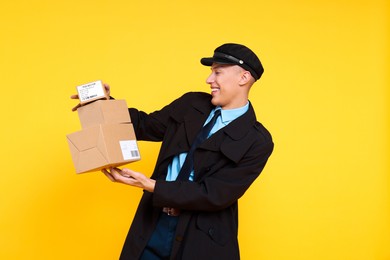 Photo of Happy postman with parcels on yellow background