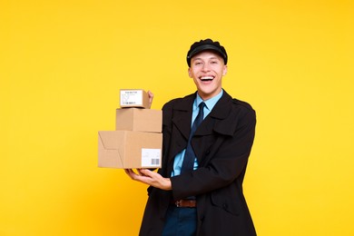 Photo of Happy postman with parcels on yellow background