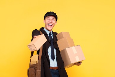 Photo of Happy postman with bag giving parcel on yellow background