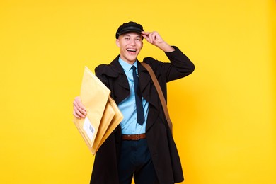 Photo of Happy postman with envelopes on yellow background