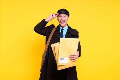 Photo of Happy postman with envelopes on yellow background