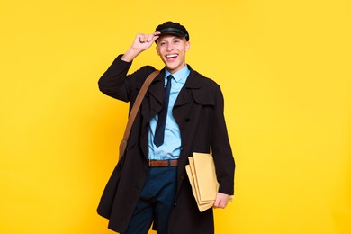 Photo of Happy postman with envelopes on yellow background