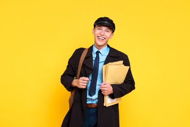 Photo of Happy postman with envelopes on yellow background