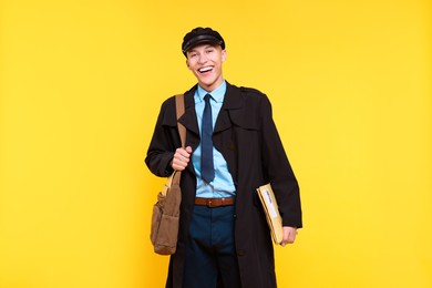 Photo of Happy postman with bag and envelopes on yellow background