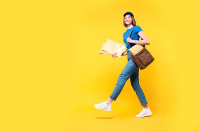 Photo of Happy postwoman with bag and envelopes on yellow background. Space for text