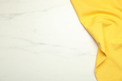 Photo of Yellow tablecloth on white marble background, top view. Space for text