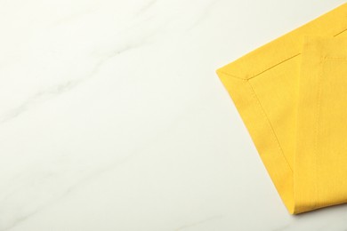 Photo of Yellow tablecloth on white marble background, top view. Space for text