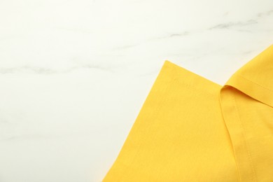 Photo of Yellow tablecloth on white marble background, top view. Space for text