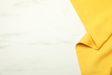 Photo of Yellow tablecloth on white marble background, top view. Space for text