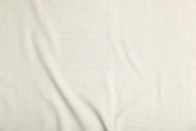 Photo of Texture of beige crumpled tablecloth as background, top view