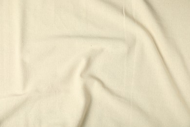 Photo of Texture of beige crumpled tablecloth as background, top view