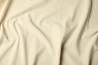 Photo of Texture of beige crumpled tablecloth as background, top view