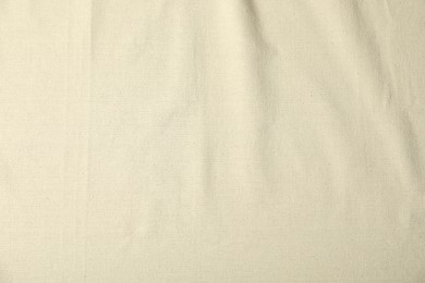 Photo of Texture of beige crumpled tablecloth as background, top view