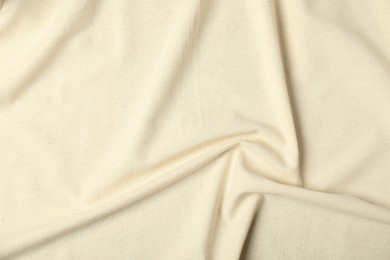 Photo of Texture of beige crumpled tablecloth as background, top view