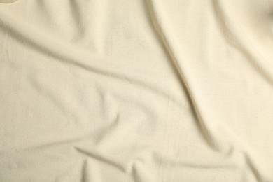 Photo of Texture of beige crumpled tablecloth as background, top view