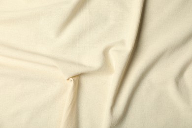 Photo of Texture of beige crumpled tablecloth as background, top view