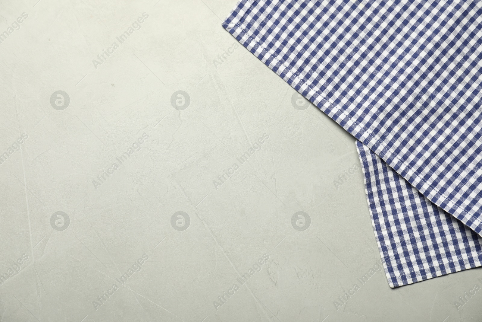 Photo of Blue checkered tablecloth on gray textured background, top view. Space for text