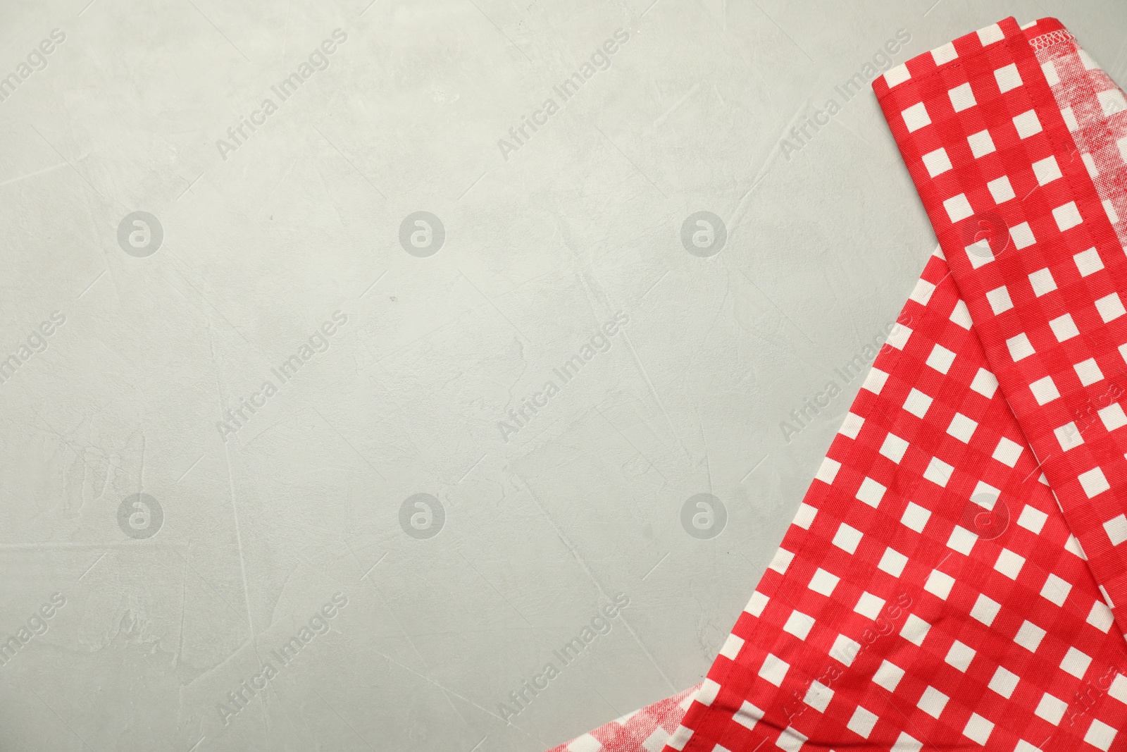 Photo of Red checkered tablecloth on gray textured background, top view. Space for text