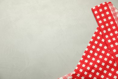 Photo of Red checkered tablecloth on gray textured background, top view. Space for text