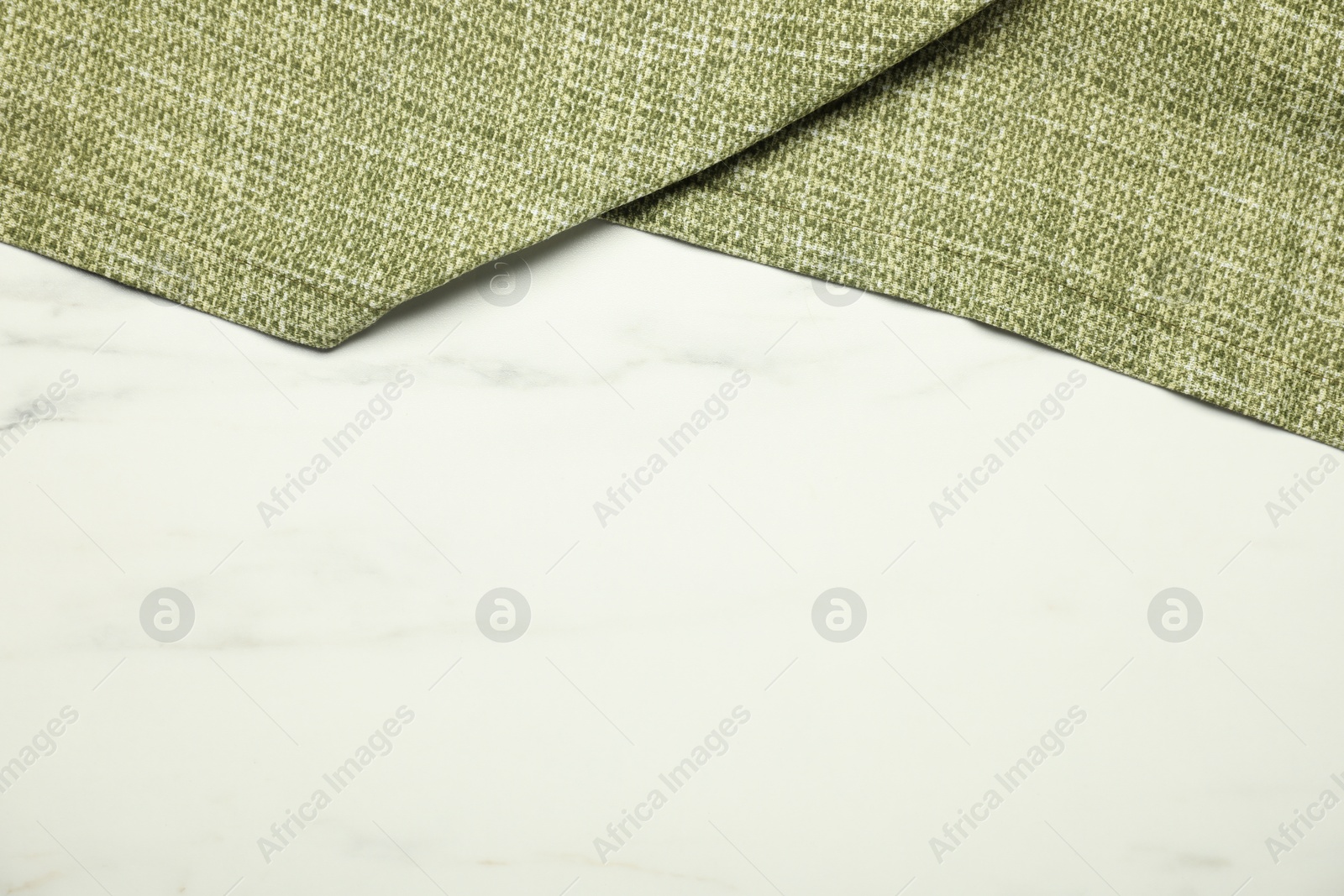 Photo of Green tablecloth on white marble background, top view. Space for text