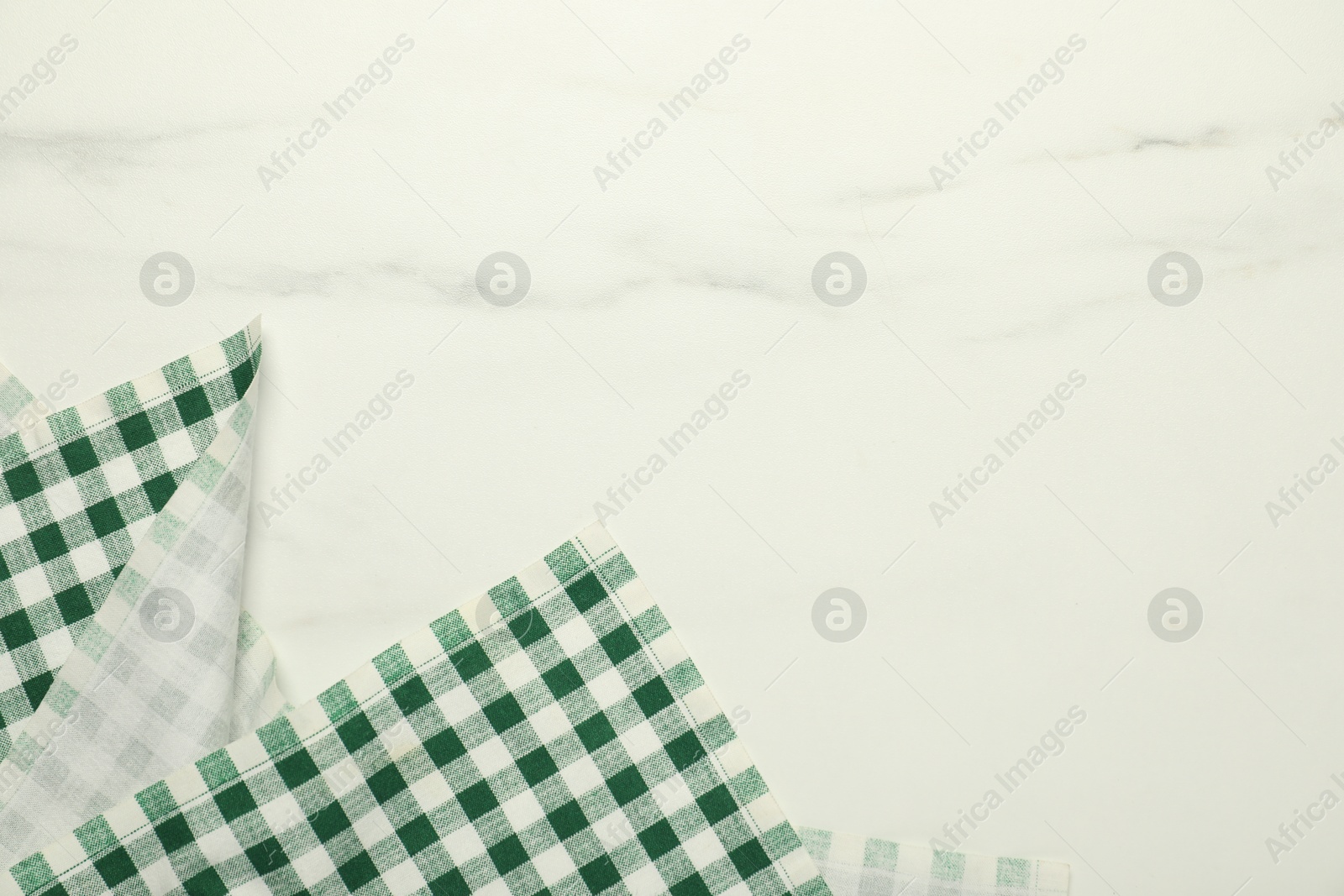 Photo of Green checkered tablecloth on white marble background, top view. Space for text