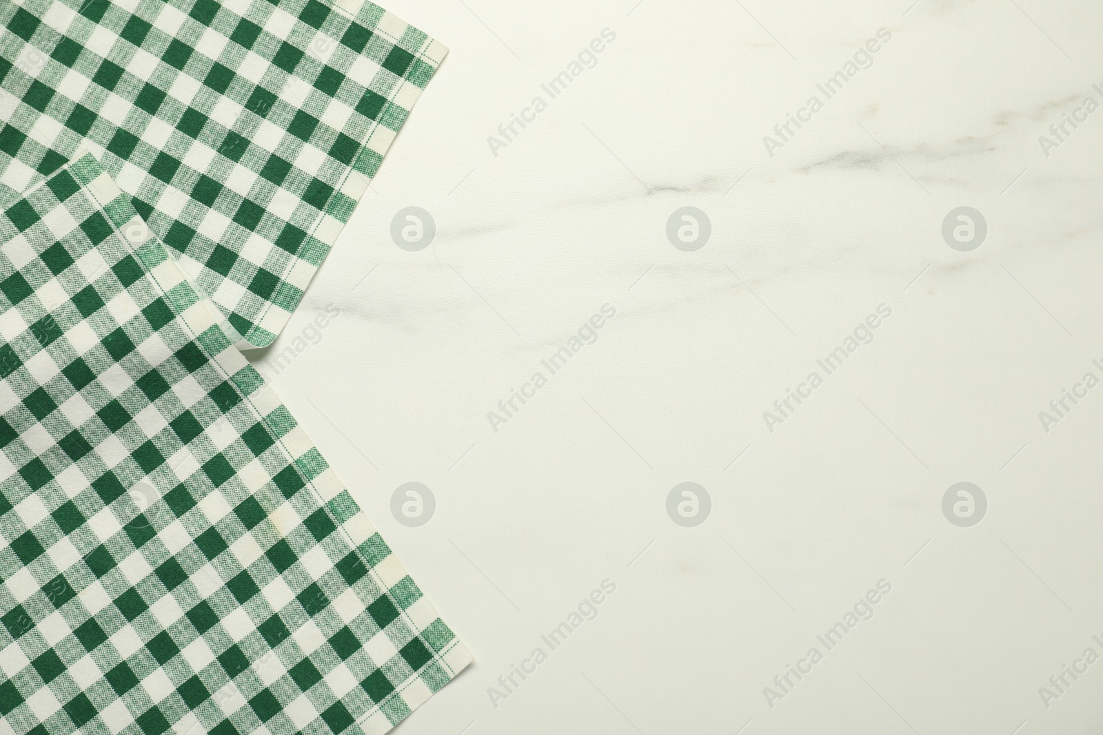 Photo of Green checkered tablecloth on white marble background, top view. Space for text