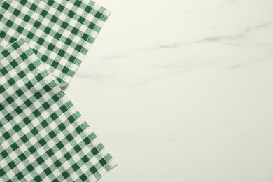 Photo of Green checkered tablecloth on white marble background, top view. Space for text