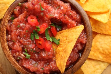 Photo of Delicious spicy salsa sauce in bowl and nacho chips on table, top view