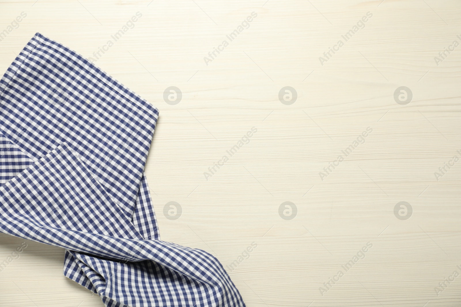 Photo of Checkered tablecloth on white wooden background, top view. Space for text