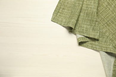 Photo of Green tablecloth on white wooden background, top view. Space for text