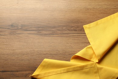 Photo of Yellow tablecloth on wooden background, top view. Space for text