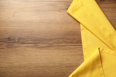 Photo of Yellow tablecloth on wooden background, top view. Space for text