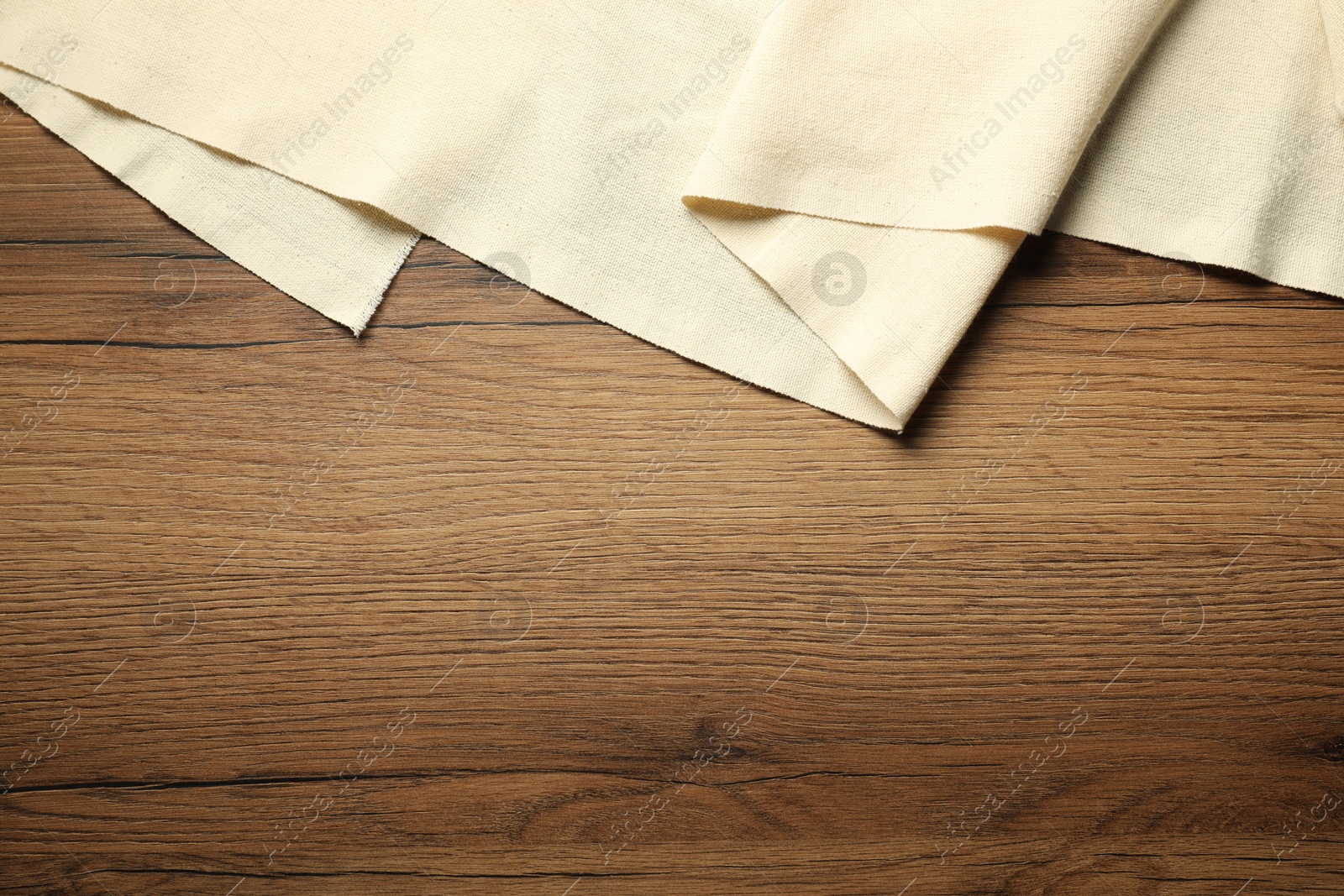 Photo of Beige tablecloth on wooden background, top view. Space for text