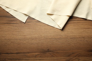 Photo of Beige tablecloth on wooden background, top view. Space for text